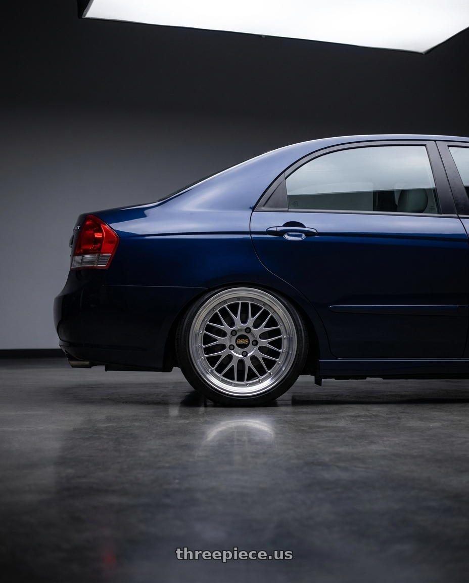2007 Kia Cerato Dark Blue with BBS LM 4x100 17x7.5+40 Diamond Silver wheels rear three quarter view square tires