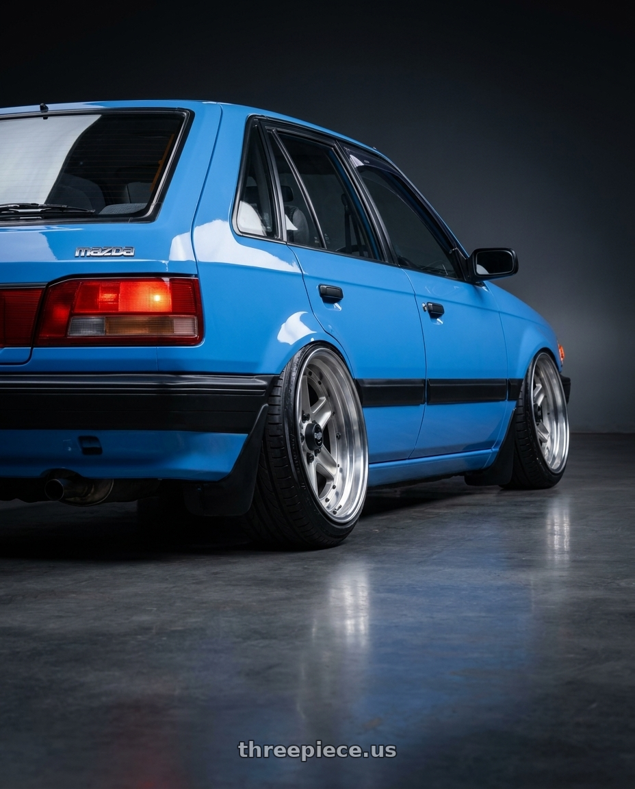 1992 Mazda 323 hatchback B3 in marina blue with Work Equip 40 4x114.3 15x8.5 +29 a disk Brut Silver wheels rear three quarter view extreme stretch tires